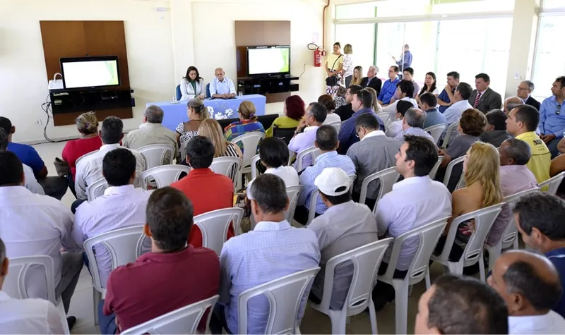 Moradores sentados em cadeiras acompanhando a mesa diretora durante assembleia de condomínio